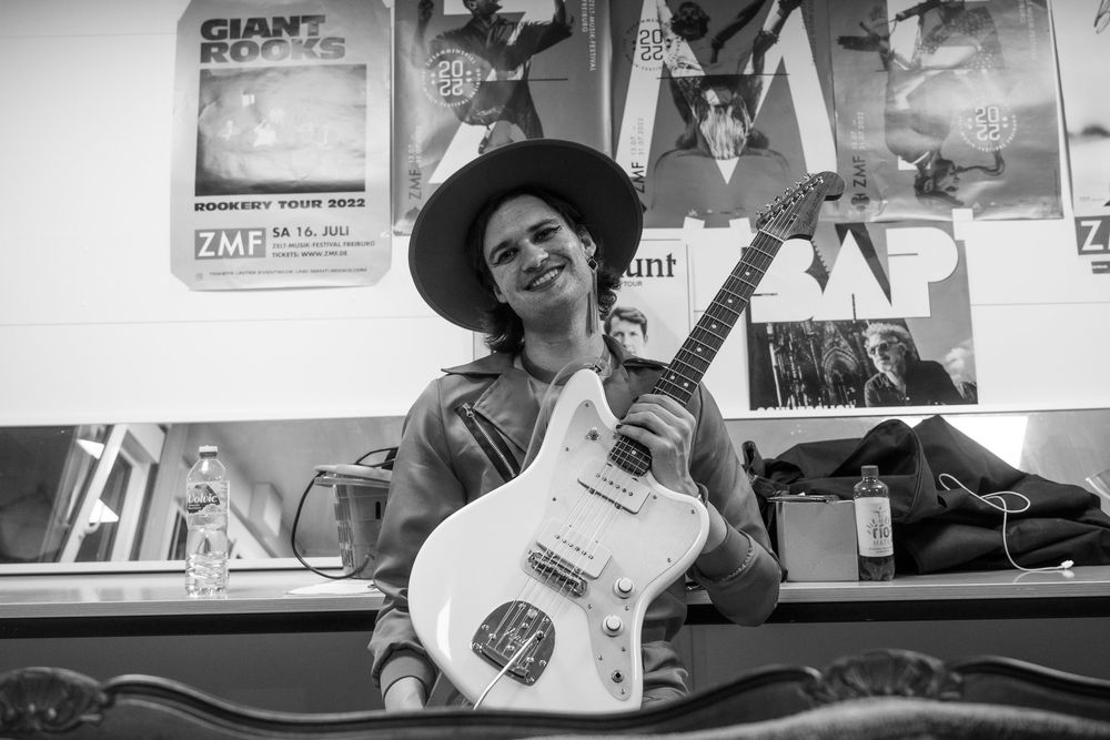 Musiker mit Hut und Gitarre im Backstage, schwarzweiss