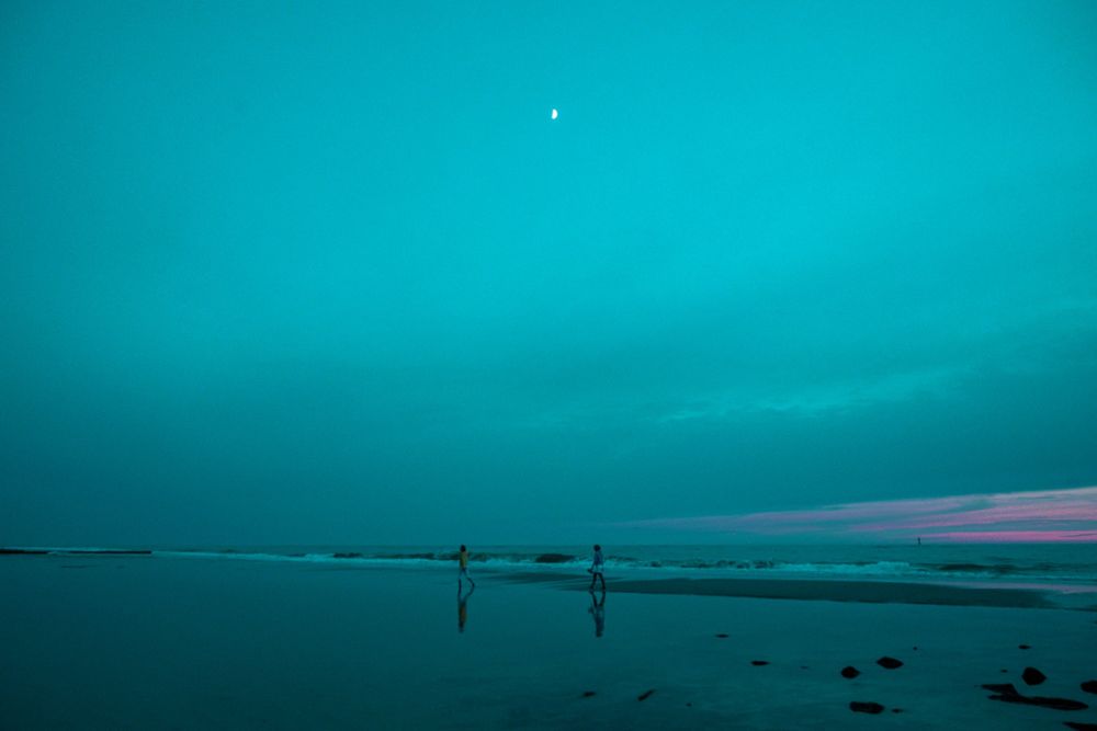 Strand mit zwei Figuren in türkisem Licht