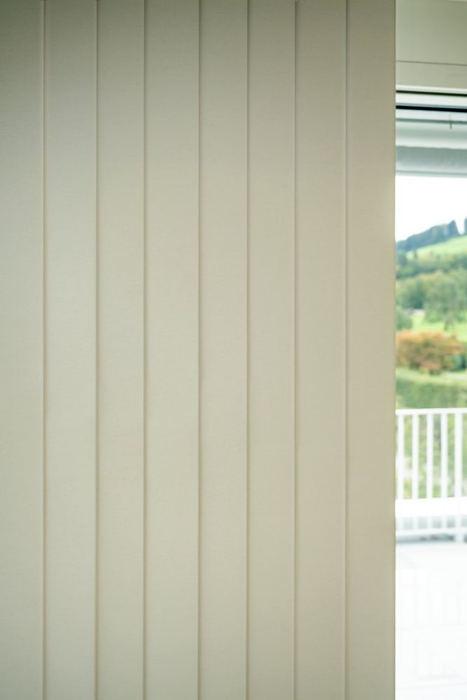 Helle Lamellen vor einem Fenster mit Blick ins Grüne
