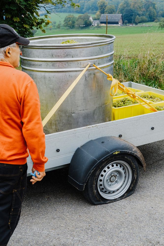 Mann in orangem Pullover neben einem Anhänger mit Stahltank